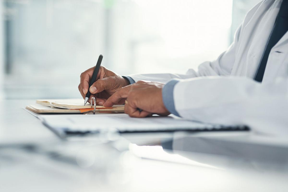 Doctor hands writing on paper at a desk